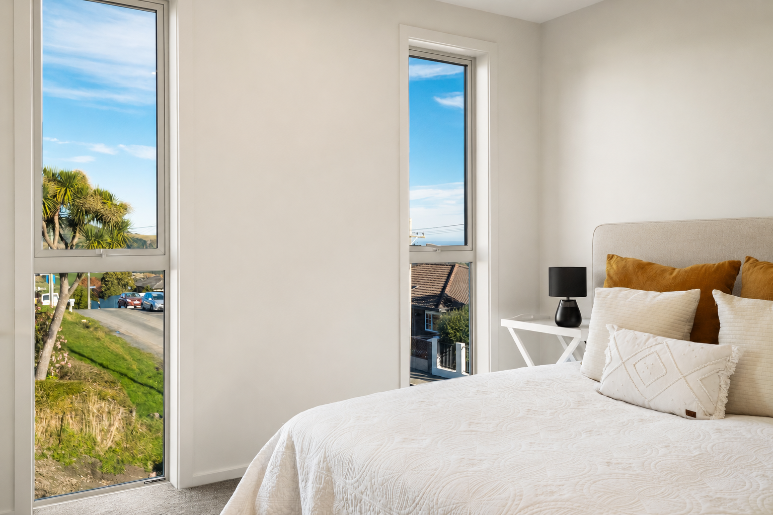 Bedroom with a simple upholstered headboard and tall windows